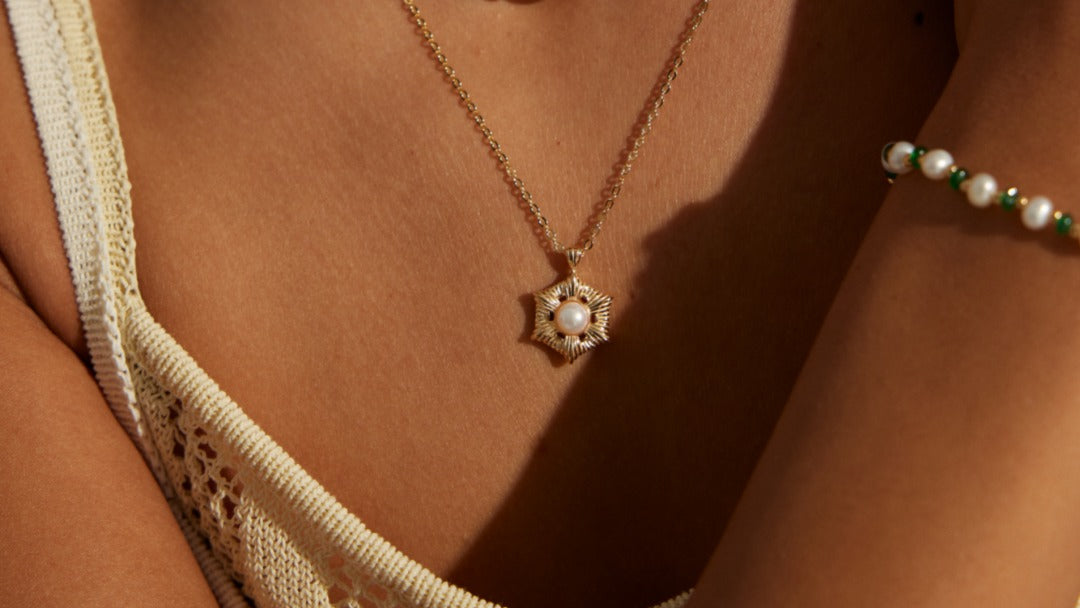 Close-up of a woman wearing a necklace with green beads and a gold pendant.